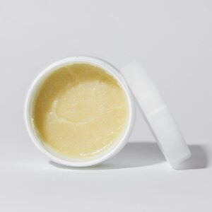 Clean and simple close-up of a cosmetic cream in a white container against a neutral background.