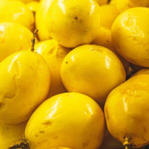 Vibrant yellow passion fruits stacked together, highlighting their freshness and texture.